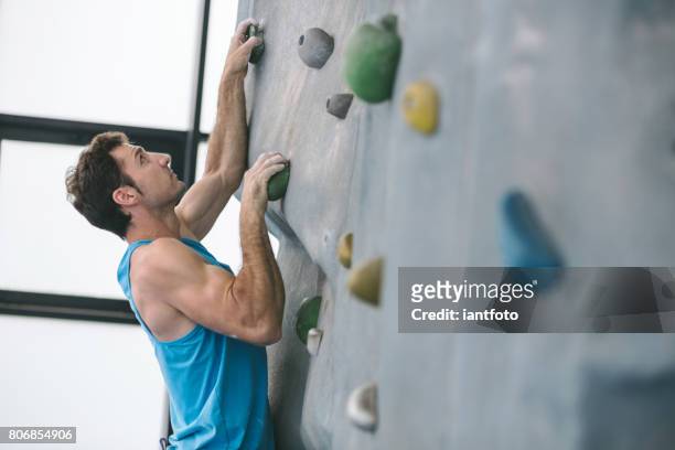 man bouldering and climbing indoor. - bouldern indoor stock pictures, royalty-free photos & images