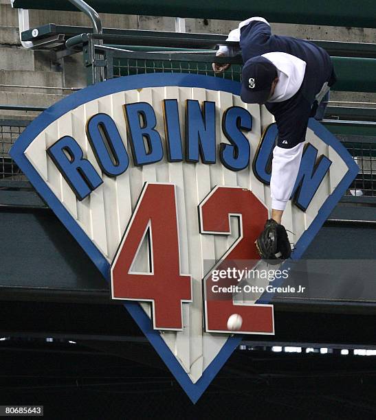 Fan reaches over the Jackie Robinson plaque for a home run ball hit during batting practice prior to the game between the Seattle Mariners and Kansas...