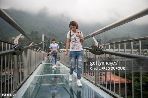 In this photo taken on June 1 tourists walk across a glass-bottomed skywalk, certified as the world's longest, at the Ordovician park in Wansheng....