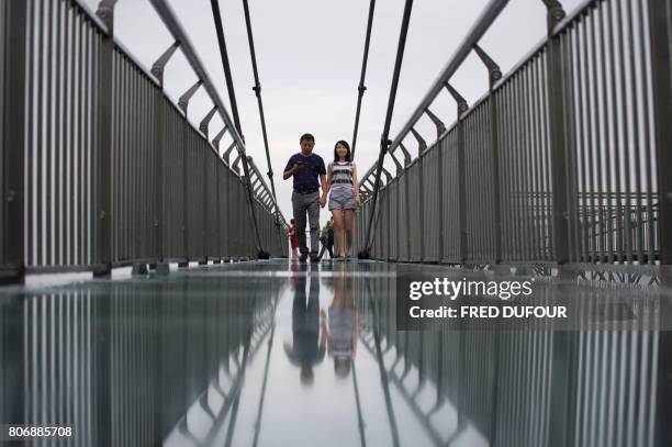 In this photo taken on June 1 a couple walks on a glass-bottomed skywalk, certified as the world's longest, at the Ordovician park in Wansheng....