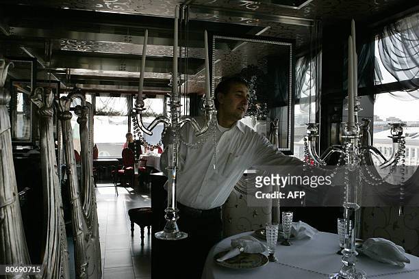 Delphine THOUVENOT Waitstaff prepare the dining hall of Russian chef Anatoly Komm's restaurant Varvara for guests in Moscow on April 2, 2008. Komm is...