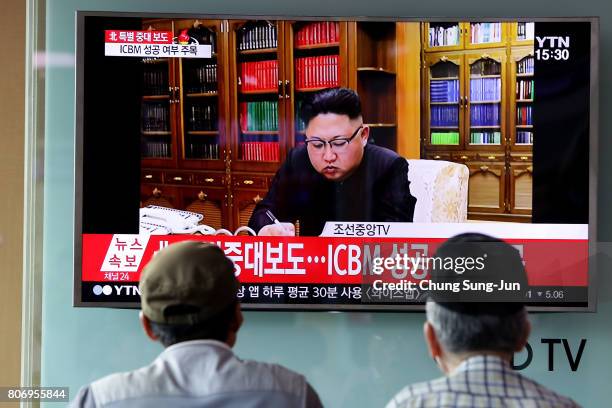 People watch a North Korea's KRT television show as a presenter announces North Korea has test-launched its first intercontinental ballistic missile...