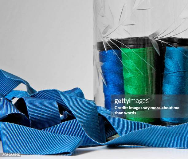 home moments - jar with vibrant blue ribbons, blue and green sewing spools - ribbon sewing item stock pictures, royalty-free photos & images