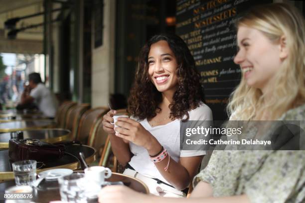 2 young women to the terrace of a parisian coffee - paris france fotografías e imágenes de stock