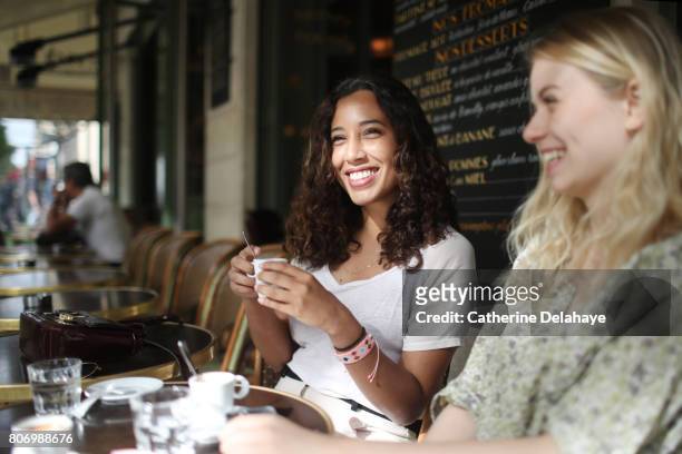 2 young women to the terrace of a parisian coffee - sidewalk cafe stock pictures, royalty-free photos & images