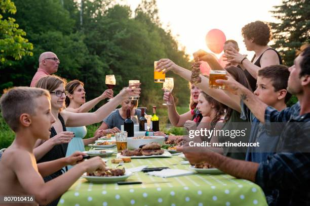 big family barbecue gathering at sunset, summer outdoors. - beer on table stock pictures, royalty-free photos & images