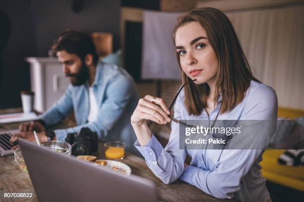 beautiful young woman working in office with her colleague - average photo editing by professional photographers stock pictures, royalty-free photos & images