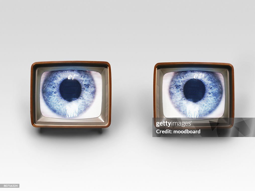 Two old fashioned TV sets with blue eyes in studio shot
