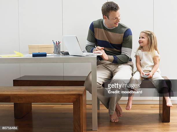 father and daughter using laptop and cell phone - business revenge stock pictures, royalty-free photos & images
