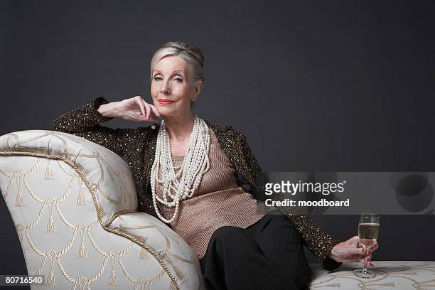mature woman having glass of champagne - formal portrait stock-fotos und bilder