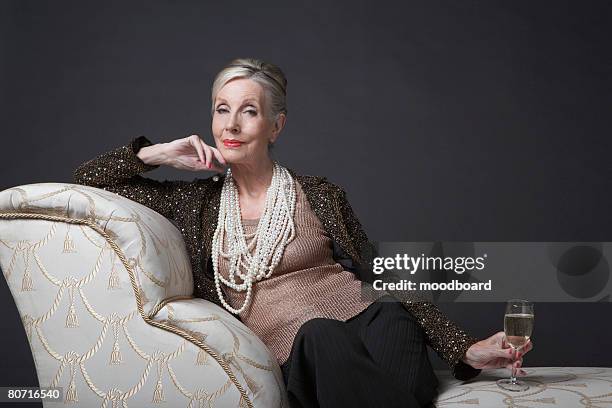 mature woman having glass of champagne - older woman in expensive jewelry stock pictures, royalty-free photos & images