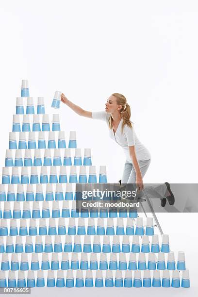 woman building pyramid of cups - 三角錐 ストックフォトと画像