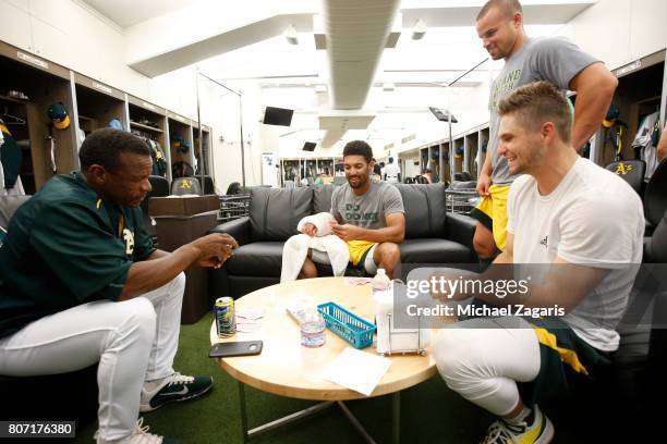 Rickey Henderson, Marcus Semien, Jake Smolinski and Kendall Graveman of the Oakland Athletics play cards in the clubhouse prior to the game against...