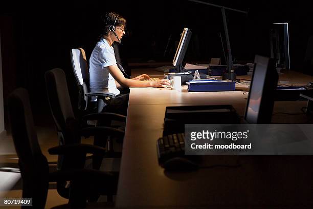 woman working in dark office - resonar fotografías e imágenes de stock