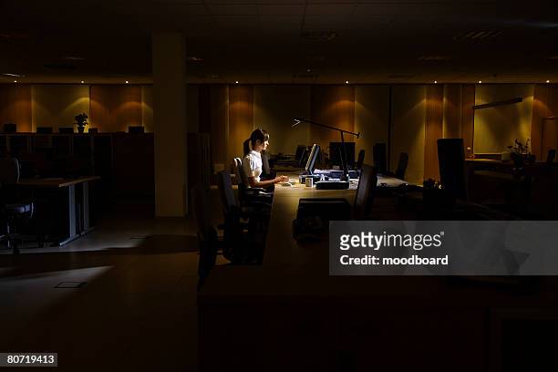 woman working in dark office - loneliness work stock pictures, royalty-free photos & images
