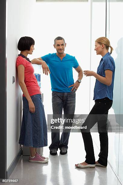 three office workers meeting by water cooler - trinkwasserbehälter stock-fotos und bilder