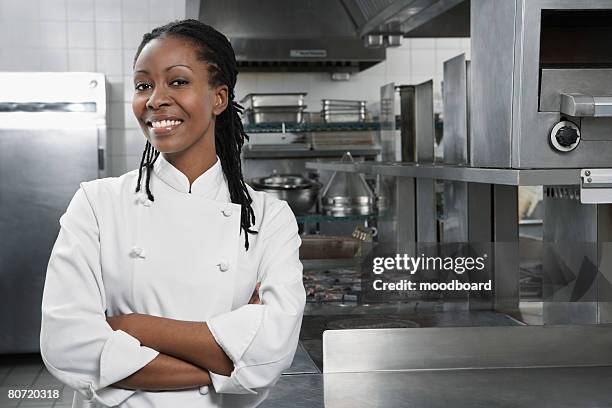 female chef with arms crossed in kitchen portrait - chef's whites stock-fotos und bilder