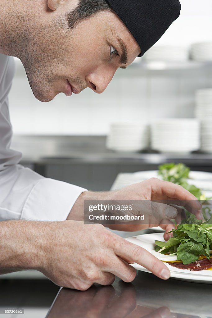 Male chef preparing salad in kitchen close-up