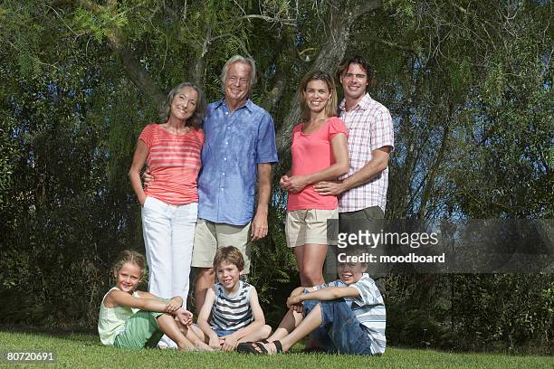 portrait of three-generation family with three children (6-11) under tree - family formal portrait stock pictures, royalty-free photos & images