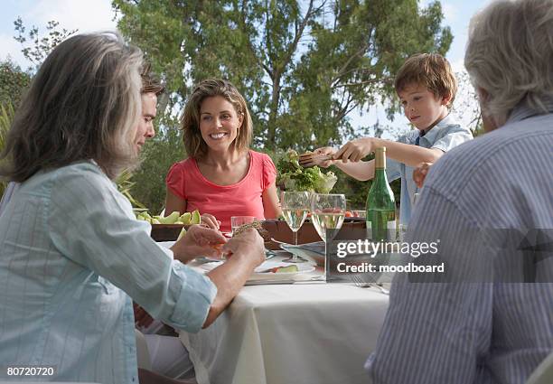 three-generation family including boy (5-6) dining in garden - white dinner stockfoto's en -beelden