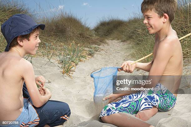 two boys (6-11) in sand dunes playing with fishing net - sifting stock pictures, royalty-free photos & images
