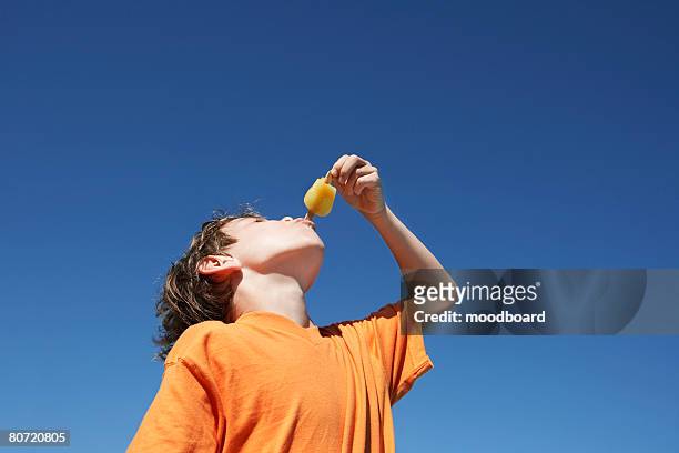 boy (7-9) eating popsicle blue sky - popsicle stock pictures, royalty-free photos & images