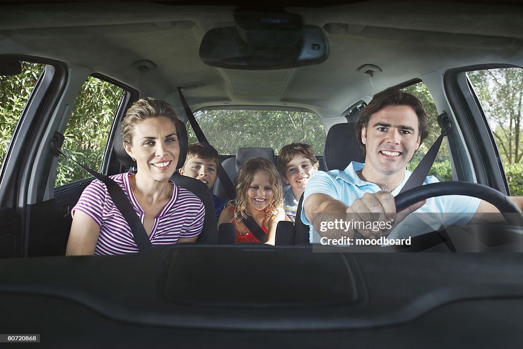 Family with three children (5-11) in car interior portrait