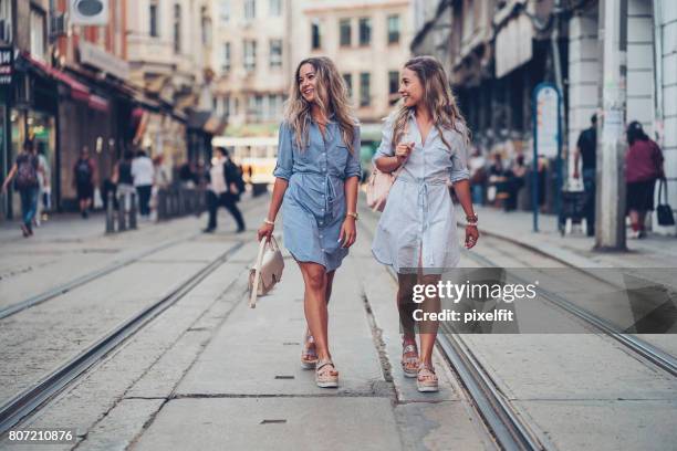 schwestern zusammen spazieren - white dress street style stock-fotos und bilder