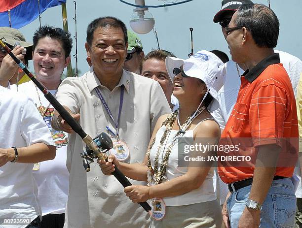 Philippine President Gloria Arroyo , flanked by local officials, casts a ceremonial fishing rod on April 17, 2008 to launch the First Siargao...