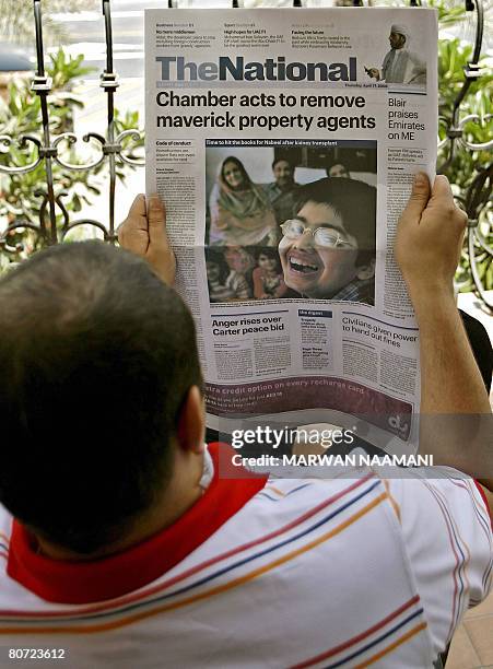 Man reads the first issue of Abu Dhabi based "The National" newspaper at a balconi in Dubai on April 17, 2008. The National is part of the United...