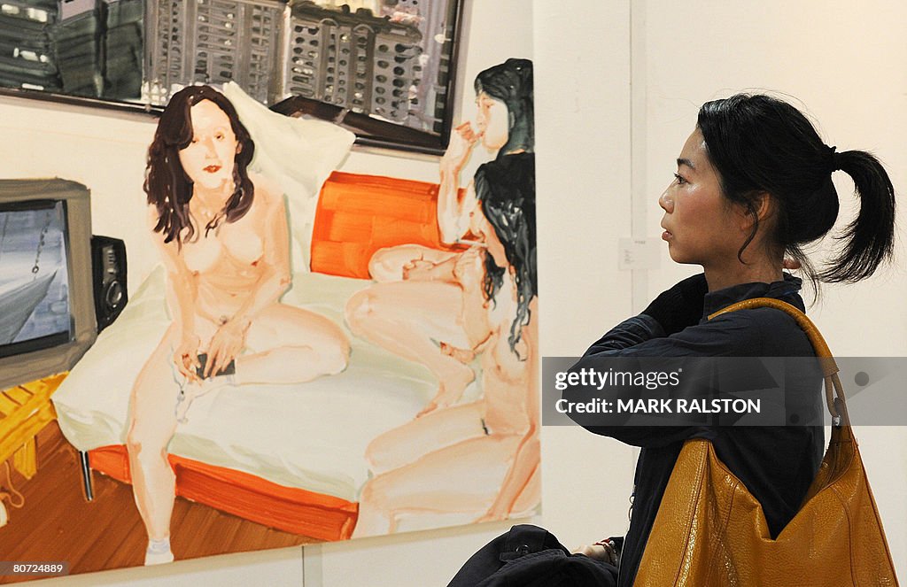 A woman views a painting depicting three