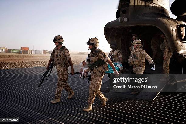 British Army Medical Emergency Response team from the UK Med Group carries injured Afghan National Army Sgt. Quem Abdulh out of the helicopter, on...