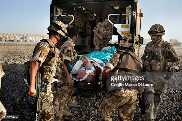British Army Medical Emergency Response team from the UK Med Group carry injured Afghan National Army Sgt. Quem Abdulh into an ambulance, on June 11...