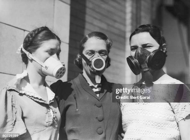 Three girls modelling various dustbowl masks to be worn in areas where the amount of dust in the air causes breathing difficulties, circa 1935.