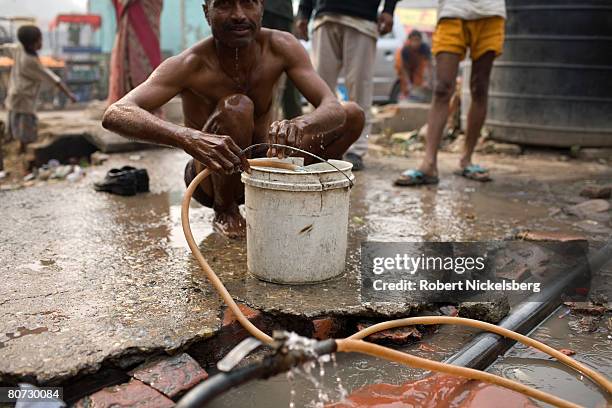 Local Indian residents in a west New Delhi slum use a broken water pipe to bathe February 6, 2008 in New Delhi, India. In a city of 16 million, 25%...