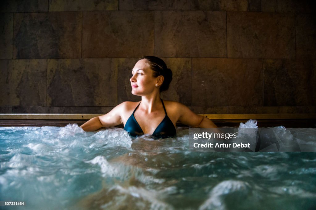 Woman relaxing in a hot tub pool during weekend days of relax and spa in a luxury place during travel vacations.