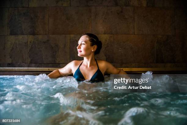 woman relaxing in a hot tub pool during weekend days of relax and spa in a luxury place during travel vacations. - hot tub - fotografias e filmes do acervo