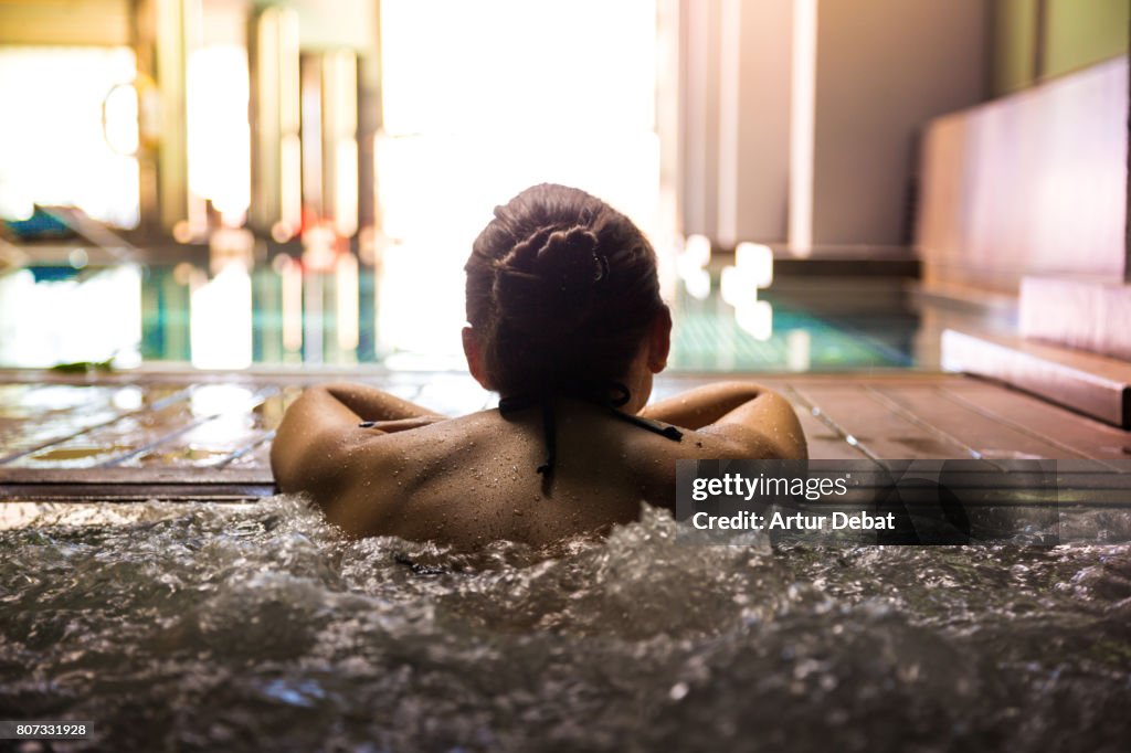 Woman relaxing in a hot tub pool during weekend days of relax and spa in a luxury place during travel vacations.