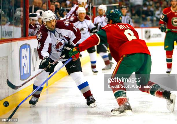 Sean Hill of the Minnesota Wild tries to stop Ian Laperriere of the Colorado Avalanche from making a pass during game five of the 2008 NHL Western...