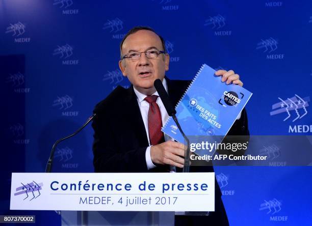 French employers' association Medef head Pierre Gattaz holds a report as he speaks during the monthly press conference at the Medef headquarters in...