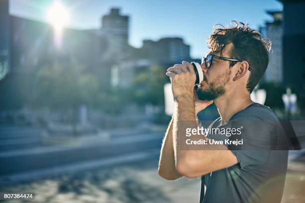 young man drinking coffee while on phone - cosmopolitan drink stock pictures, royalty-free photos & images