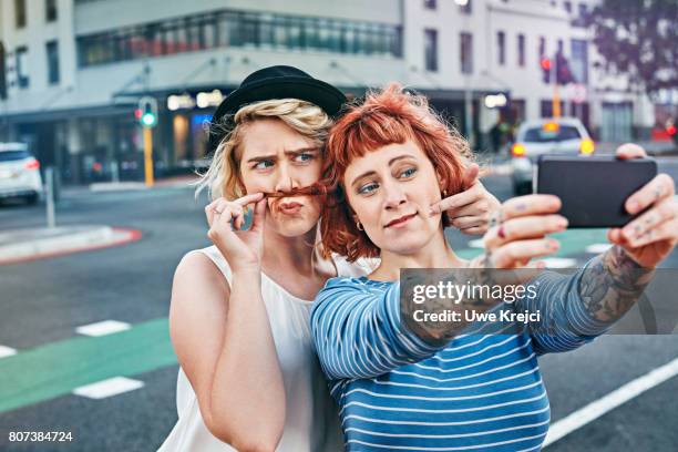 two young women taking self portrait - funny selfie stockfoto's en -beelden