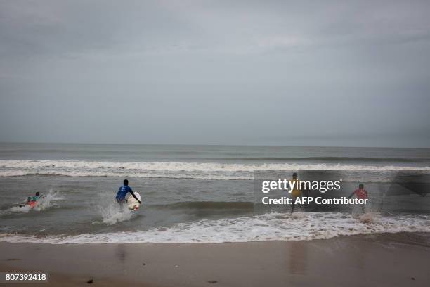 Surfers run to the waves to compete in the international surf day competition on Kokrobite Beach, Ghana, on June 18, 2017. The beach, some 30...