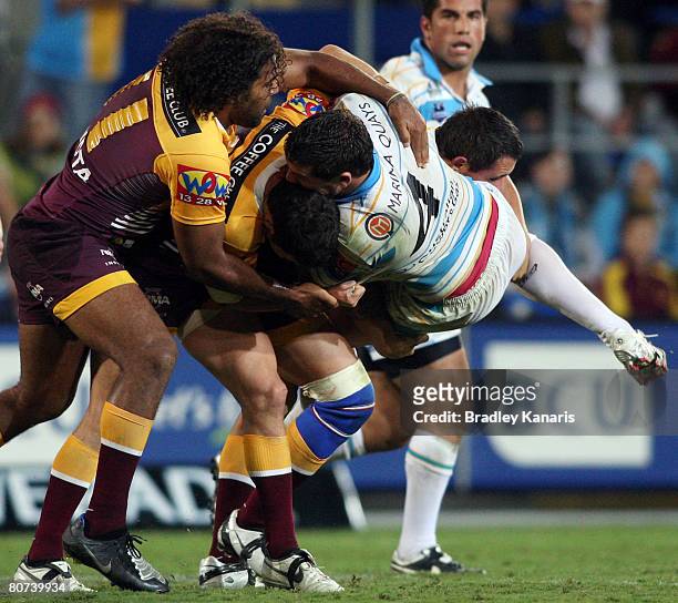 Brett Delaney is picked up by Broncos tacklers during the round six NRL match between the Gold Coast Titans and the Brisbane Broncos at Skilled...