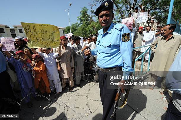 Pakistani students belonging to radical Red Mosque carry placards as they gather outside a police station to get a criminal case register against...