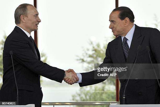 Outgoing Russian President Vladimir Putin shakes hands with Italian Prime Minister-elect Silvio Berlusconi at the end of their joint press conference...