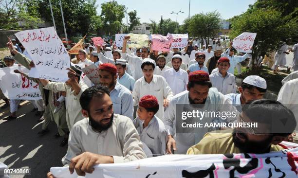 Pakistani students belonging to radical Red Mosque carry placards as they gather outside a police station to get a criminal case register against...