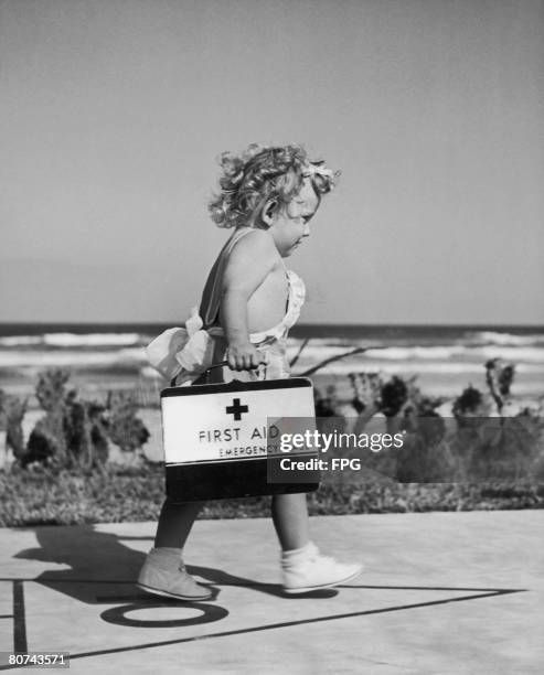 Cindy Lou Sinclair, 19 months, rushing along the seafront in Tampa Bay, Florida, with a first aid kit, circa 1942.