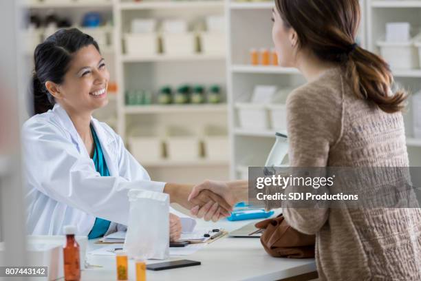 young pharmacist smiles and shakes hands with a customer - showing appreciation stock pictures, royalty-free photos & images