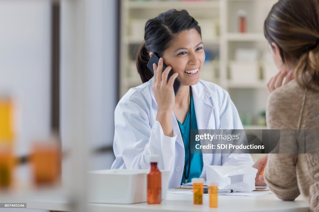 Young pharmacist helps customer get refill request from doctor